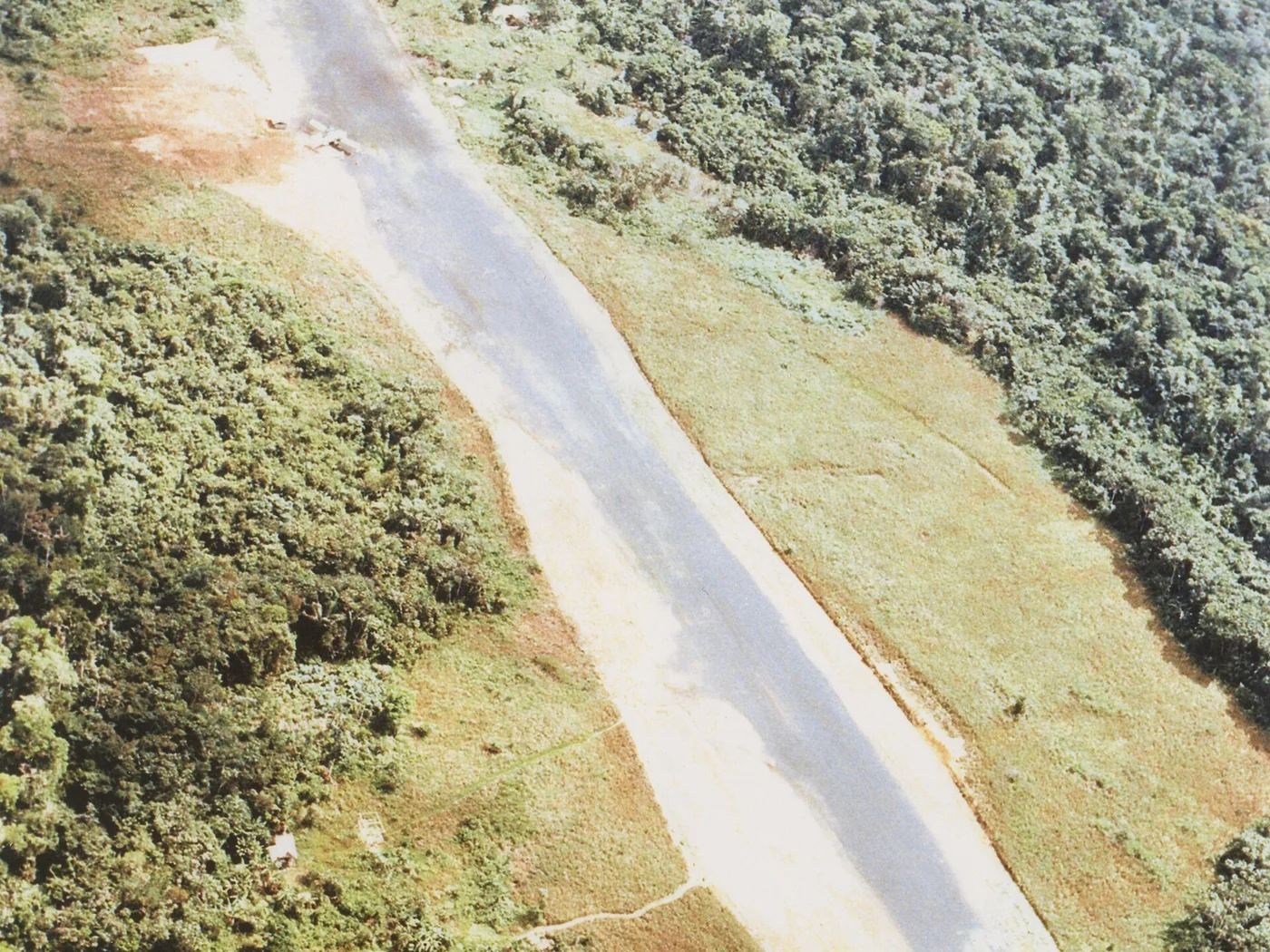 Aerial photograph of the Port Kaituma airstrip, a narrow cleared strip in dense forest.