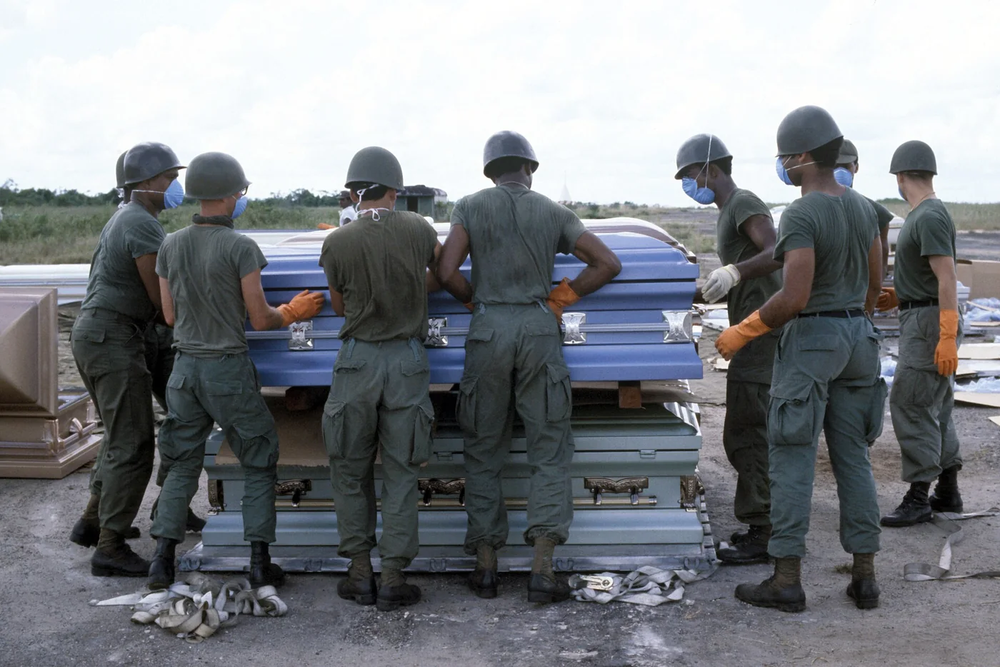 US service members in helmets and gloves handling stacked coffins on an airfield in Georgetown, Guyana.