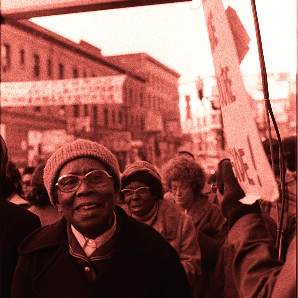 Elderly Black women, members of Peoples Temple, marching beneath the International Hotel sign in San Francisco in January 1977.